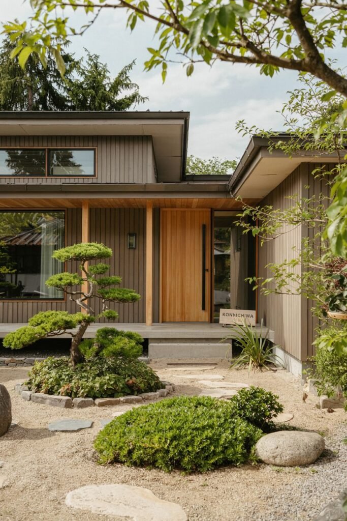 Warm wood Contemporary japandi house exterior featuring vertical siding, large wooden door, raked gravel garden, rocks, and a sign reading "KONNICHIWA".