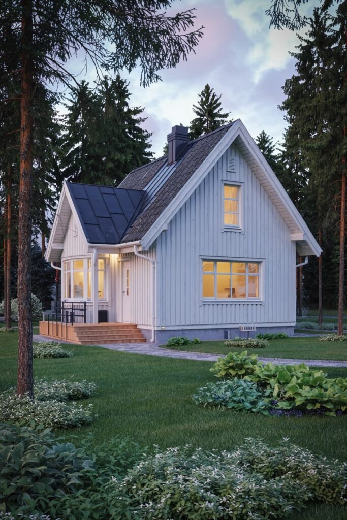 An inviting pale blue vertical-sided Scandinavian house exterior with a dark roof, a covered porch area with seating, and warm light emanating from the windows at dusk.
