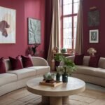 A warm room with burgundy walls, two curved light-colored sofas, a large round coffee table, and a geometric rug.